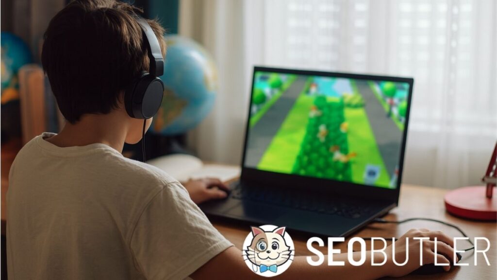 A young boy wearing headphones plays a colorful video game on a laptop at a wooden desk. A globe and a red lamp are visible in the background.